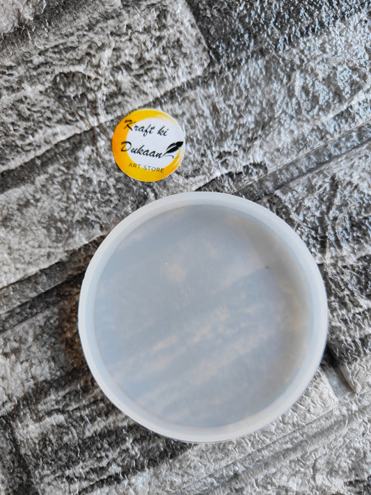 Clear round 3 inch coaster mold by Kraft ki Dukaan placed on textured gray surface