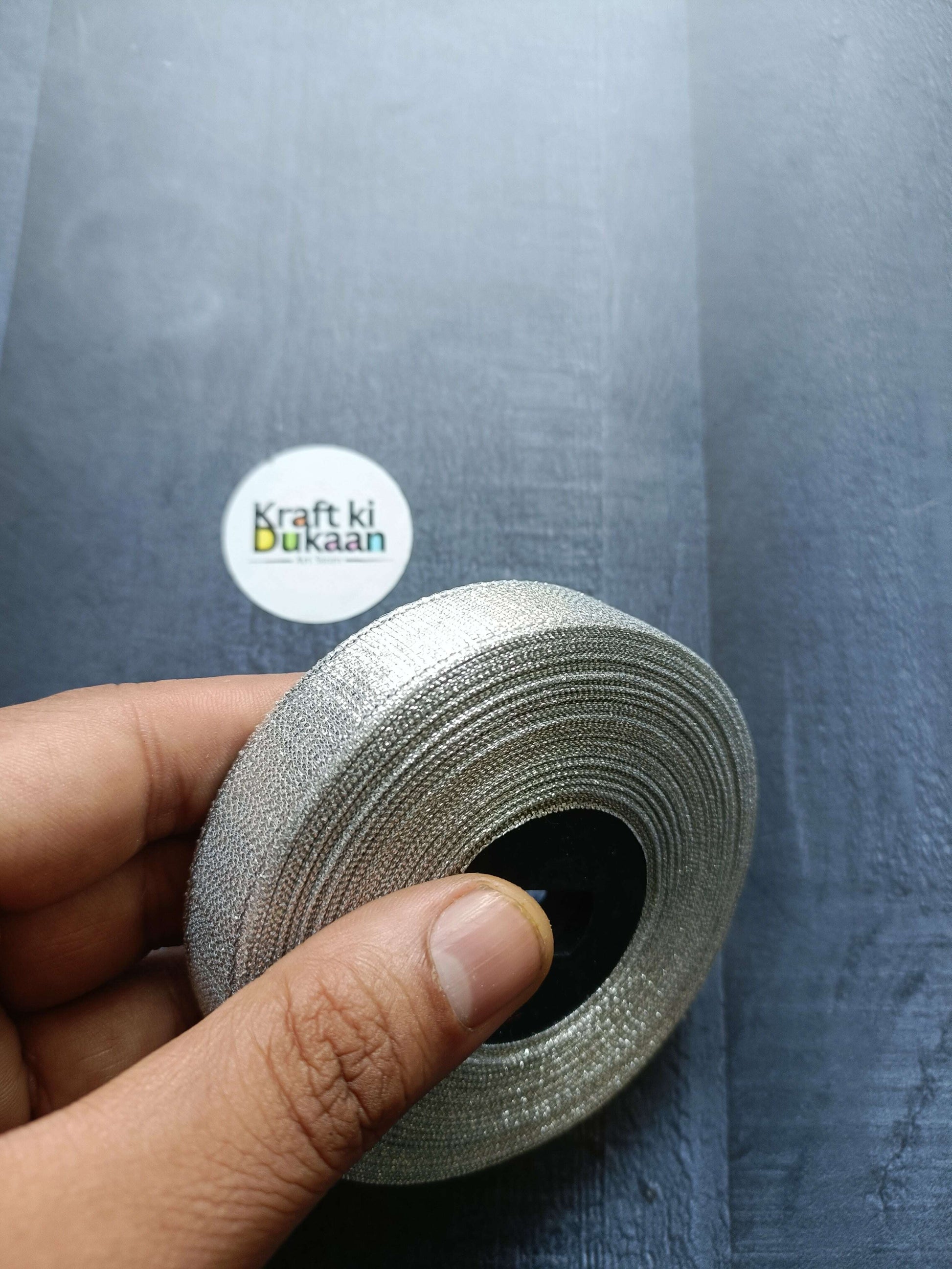 Tissue Ribbon Roll - Silver glitter ribbon roll held in hand