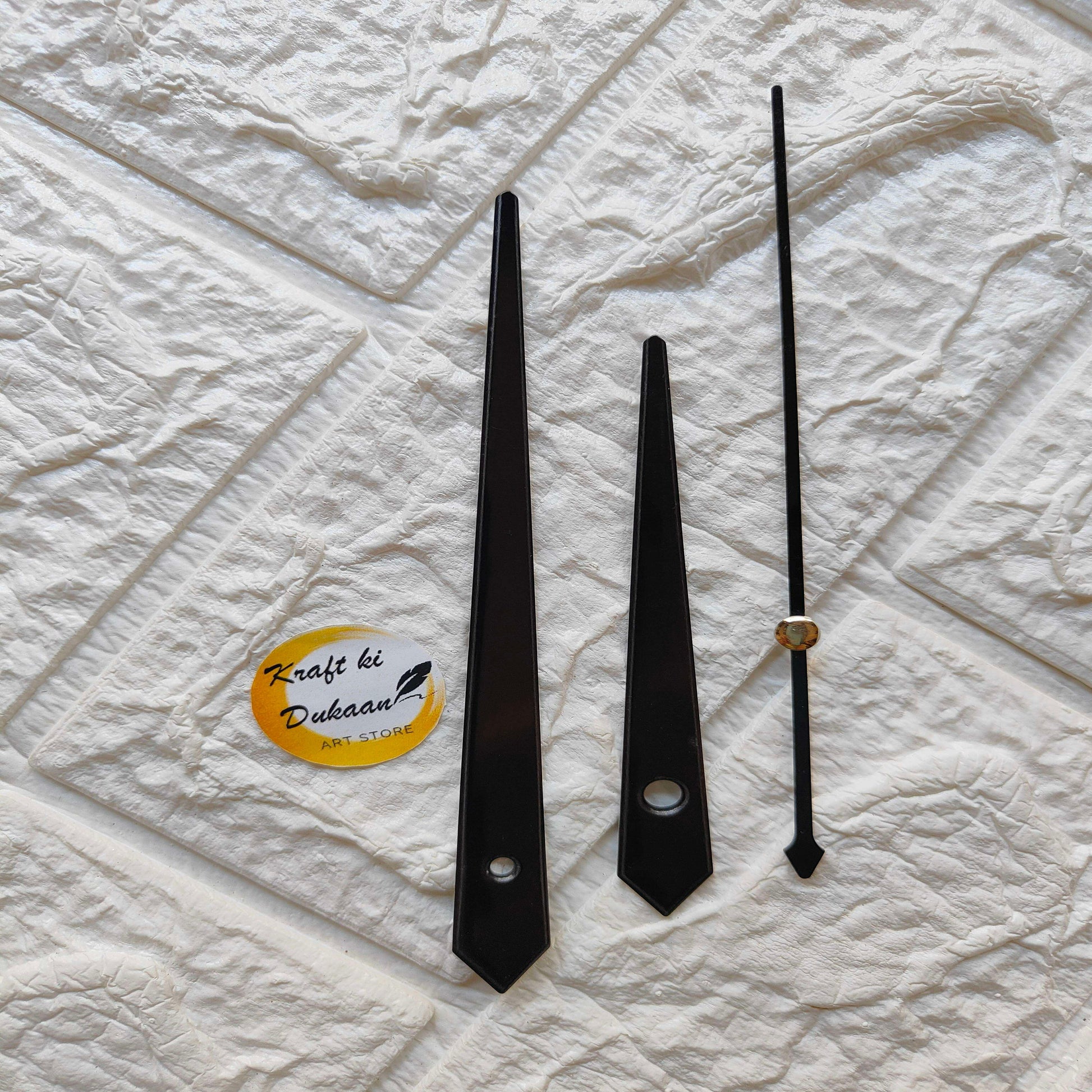Black metal clock hands set, including long thin and decorative pointed hands with brass cap.
