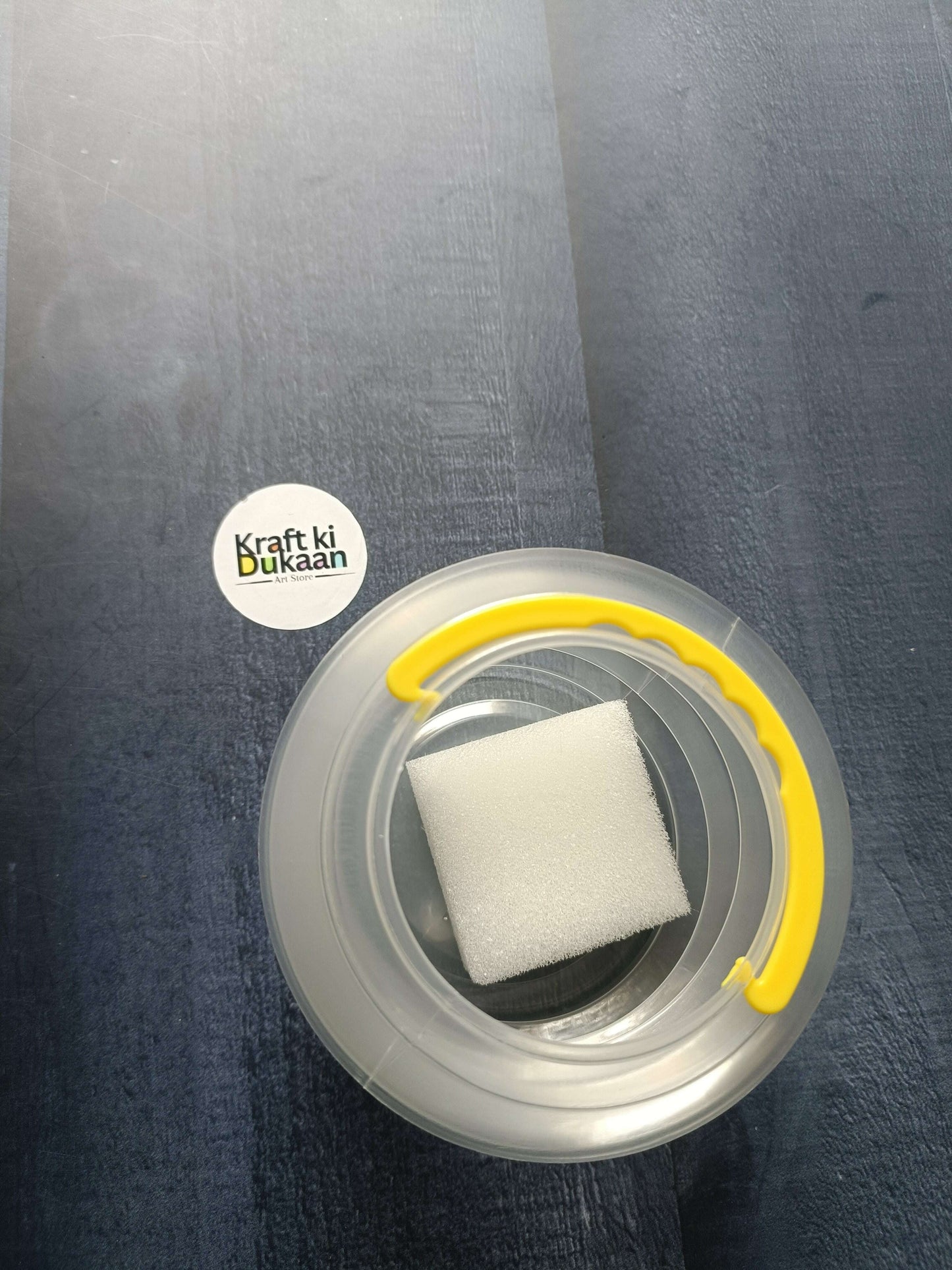 Paint brush wash bucket with yellow handle; inner area holds a white cleaning sponge.