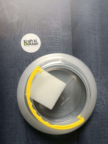 Paint brush wash bucket with yellow handle; clear circular tub containing a white sponge.