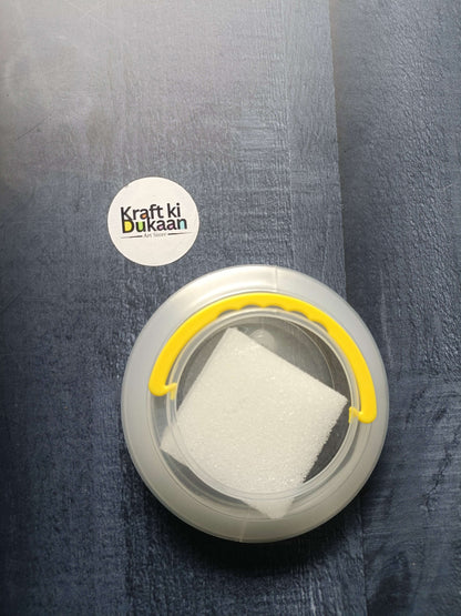 Paint brush wash bucket with yellow handle; white sponge inside clear circular tub.