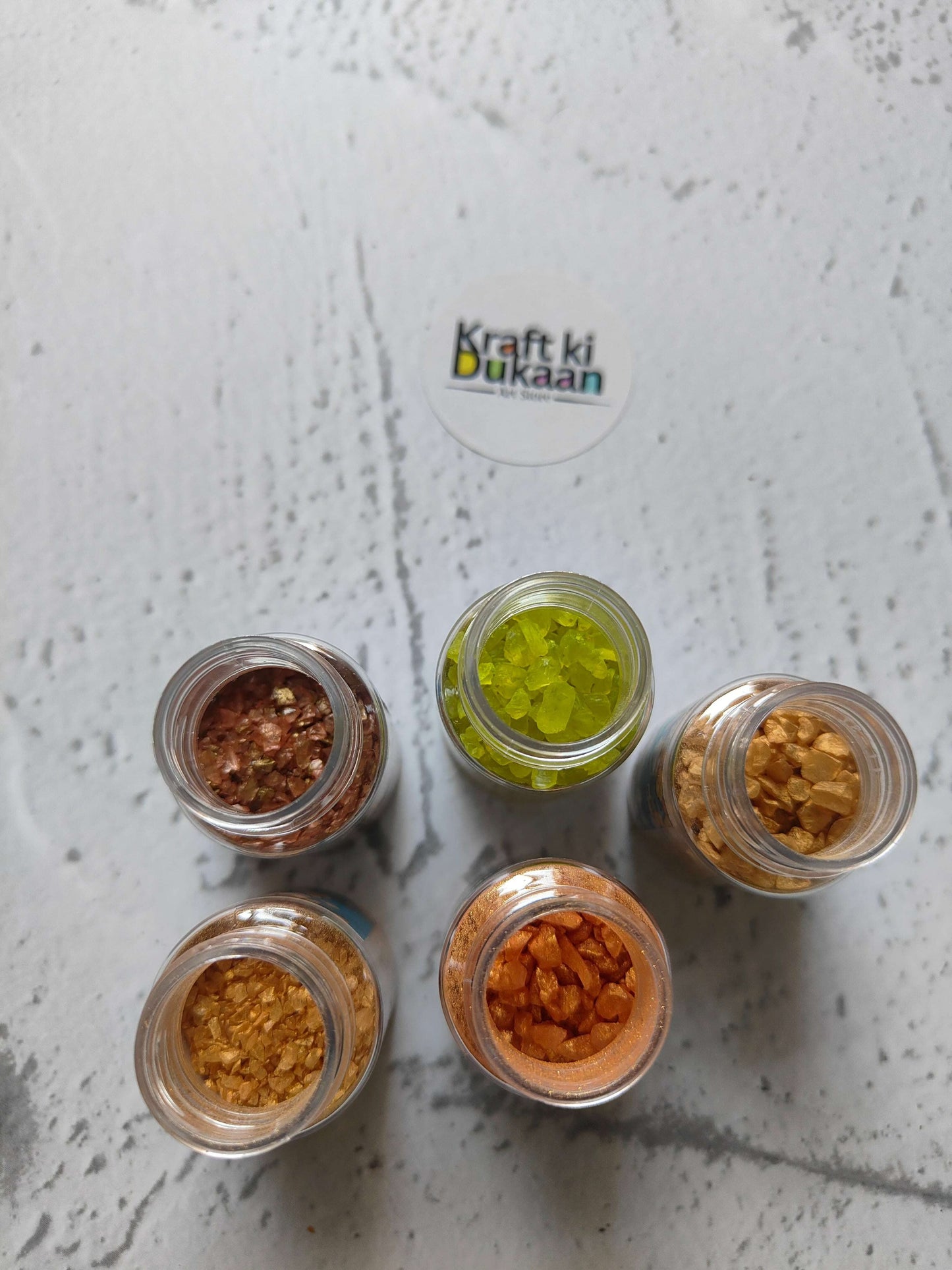 Five jars of assorted glass stone pieces: green, amber, copper and brown tones