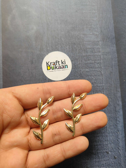 Gold metal leaf embellishments, small pointed leaves on sprig, held in hand