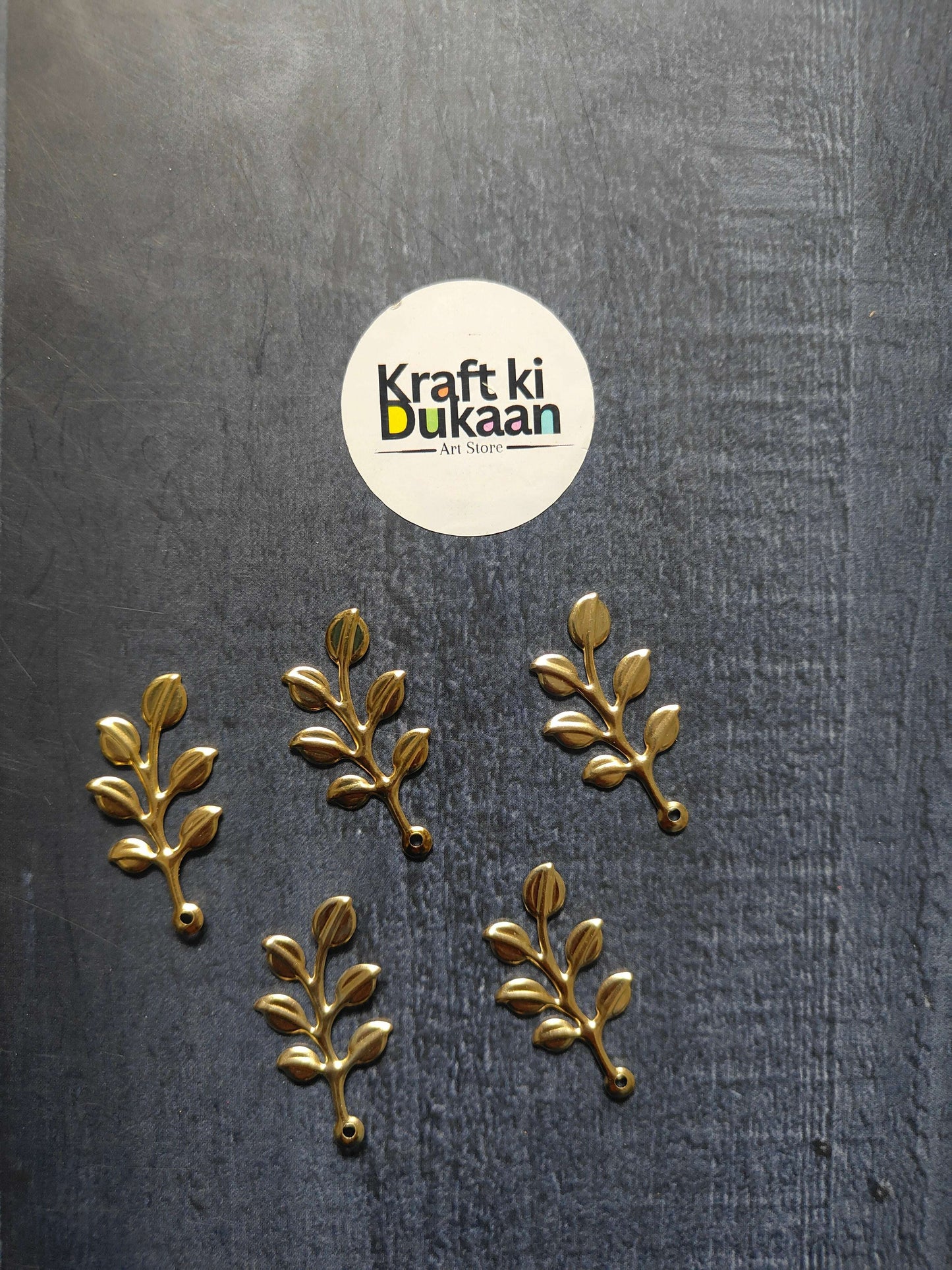 Metal leaf A17 gold sprig embellishments, multiple branches with oval leaves on fabric