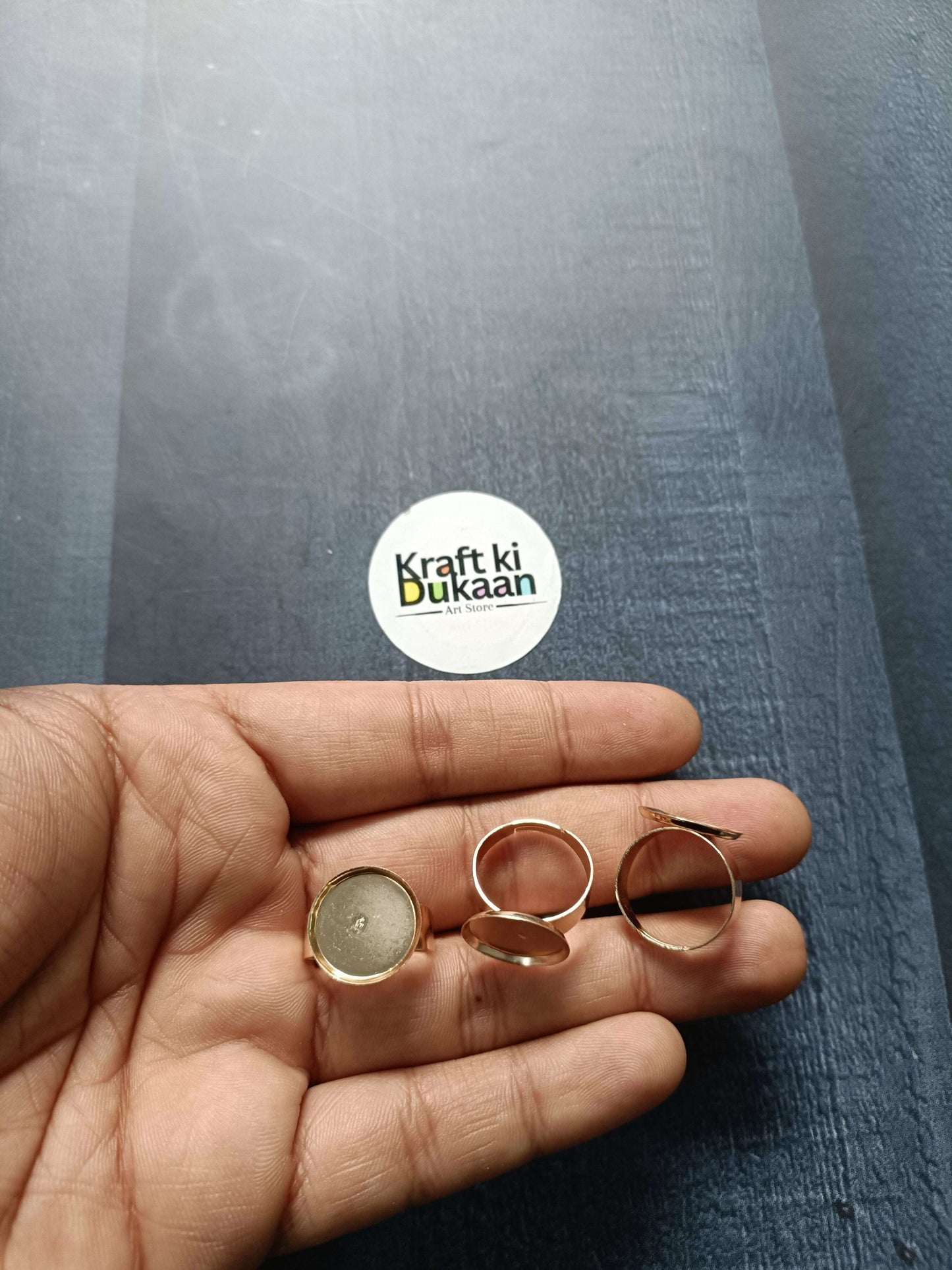 Rose-gold ring bases held in palm, open round bezel settings (4 shown)