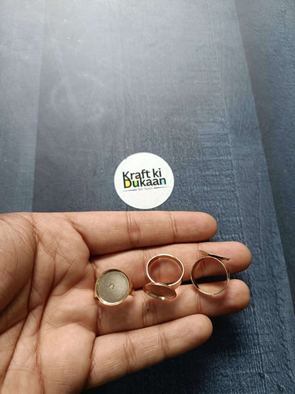 Rose-gold ring bases held in palm, open round bezel settings (4 shown)