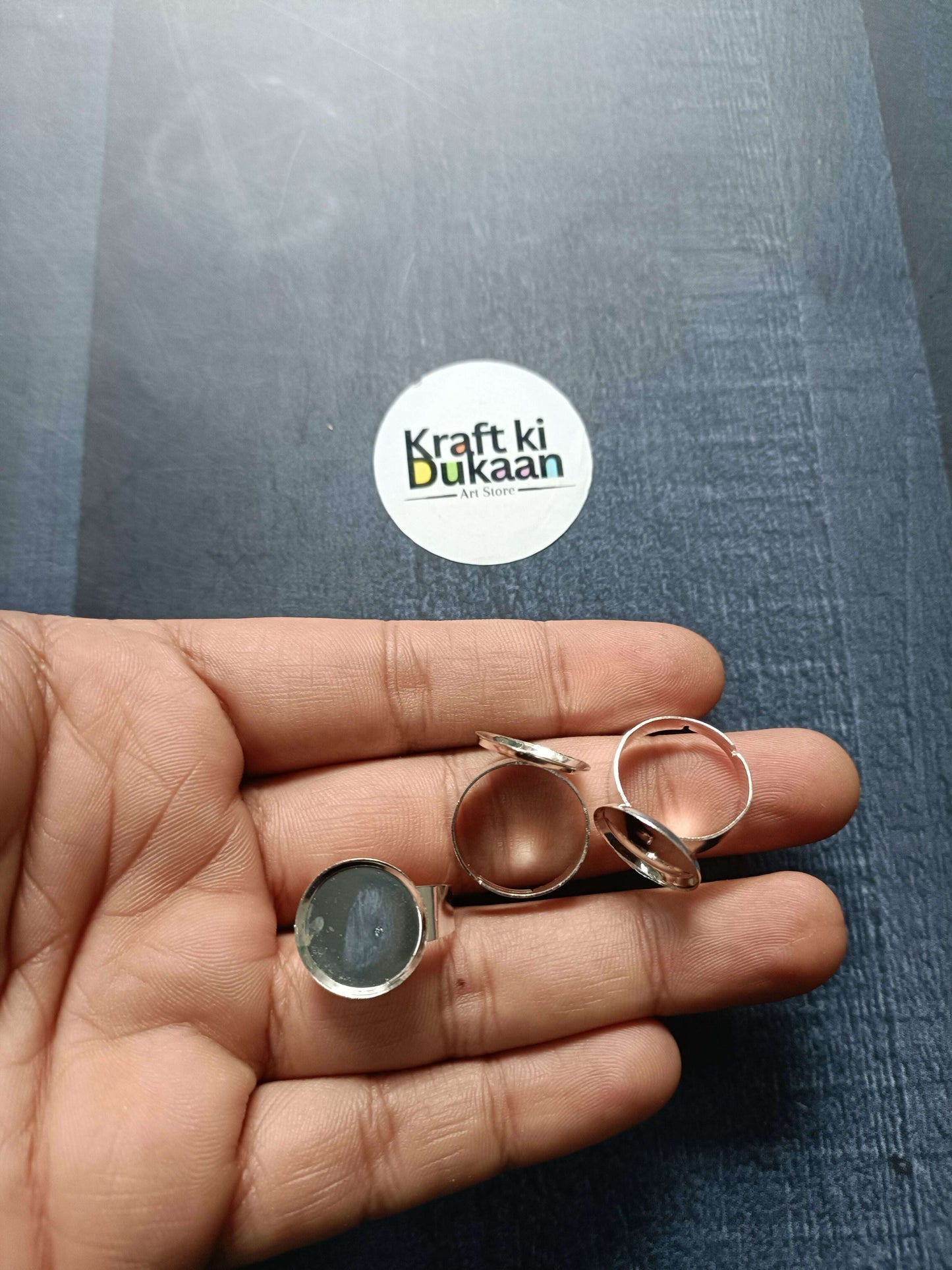 Ring bases held in hand, mixed rose-gold and silver-tone round bezel settings