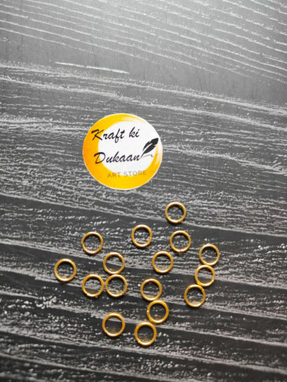 Small golden metal rings, round hoops with open centers, spread out