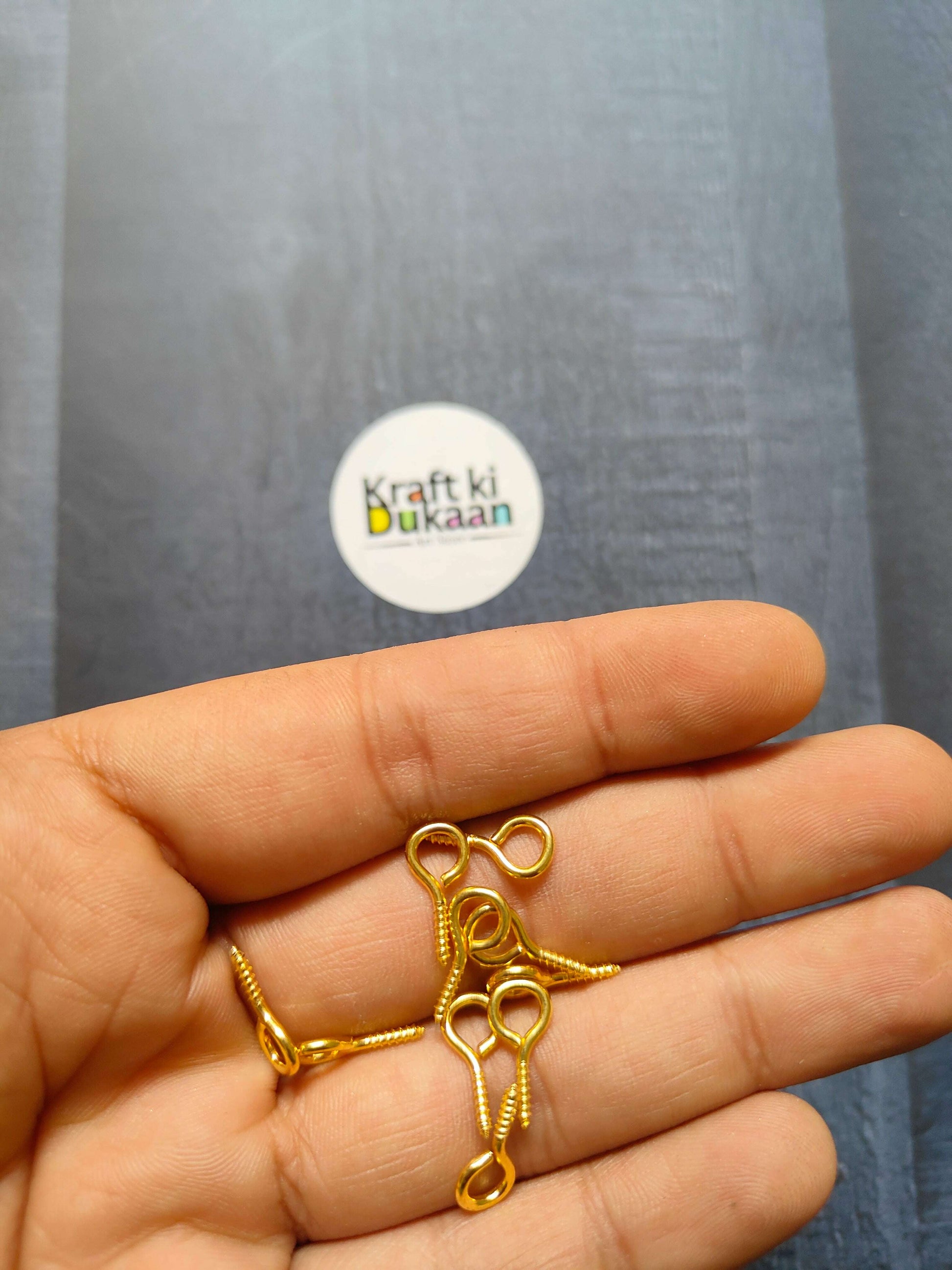 Gold eye screw hooks, looped eyes on screw shanks (close-up in hand)