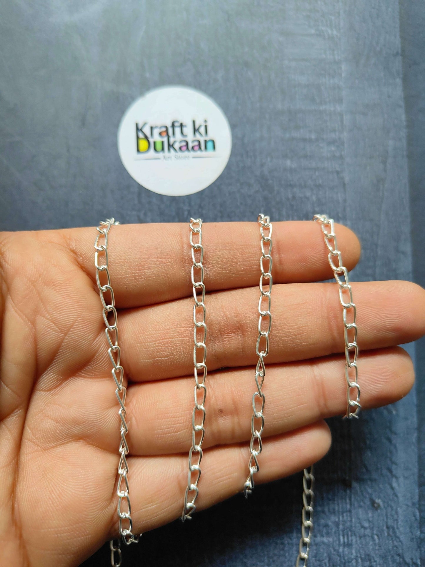Silver tone jewellery chain with chunky rectangular links, hand view