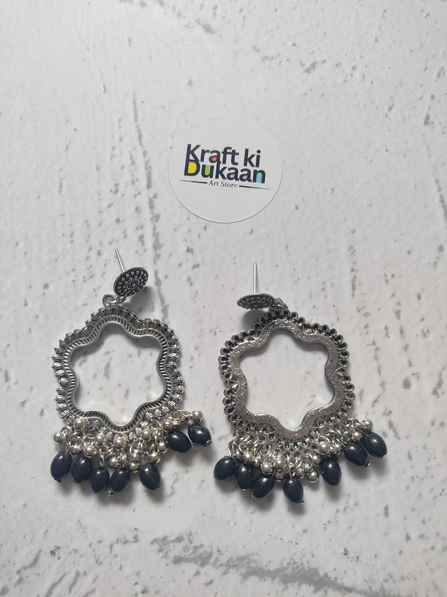 Silver flower jhumka earrings with dark blue bead drops, ornate silver-toned pair