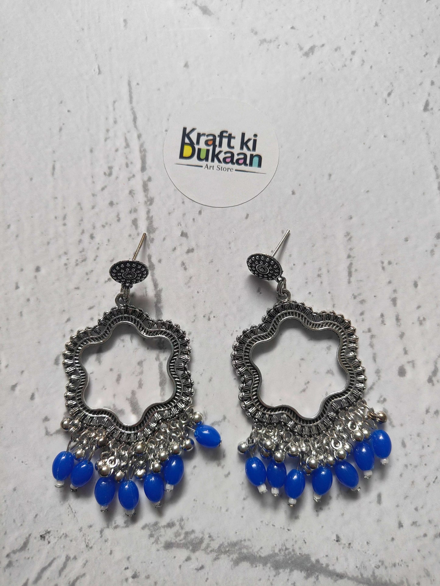 Silver flower jhumka earrings with blue bead drops, ornate silver-toned pair