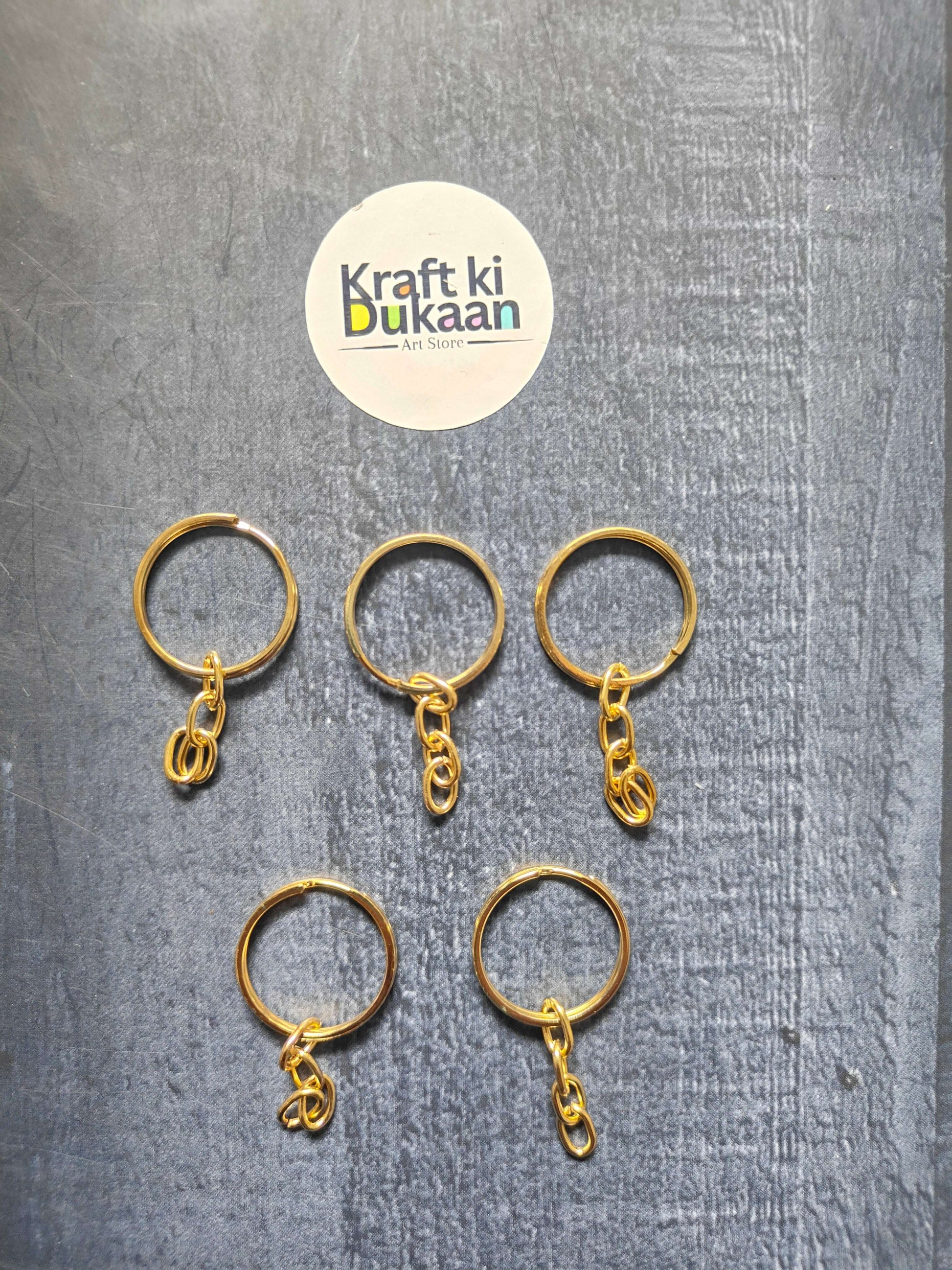 Gold-tone small keychain rings with short chain links, laid out in a row