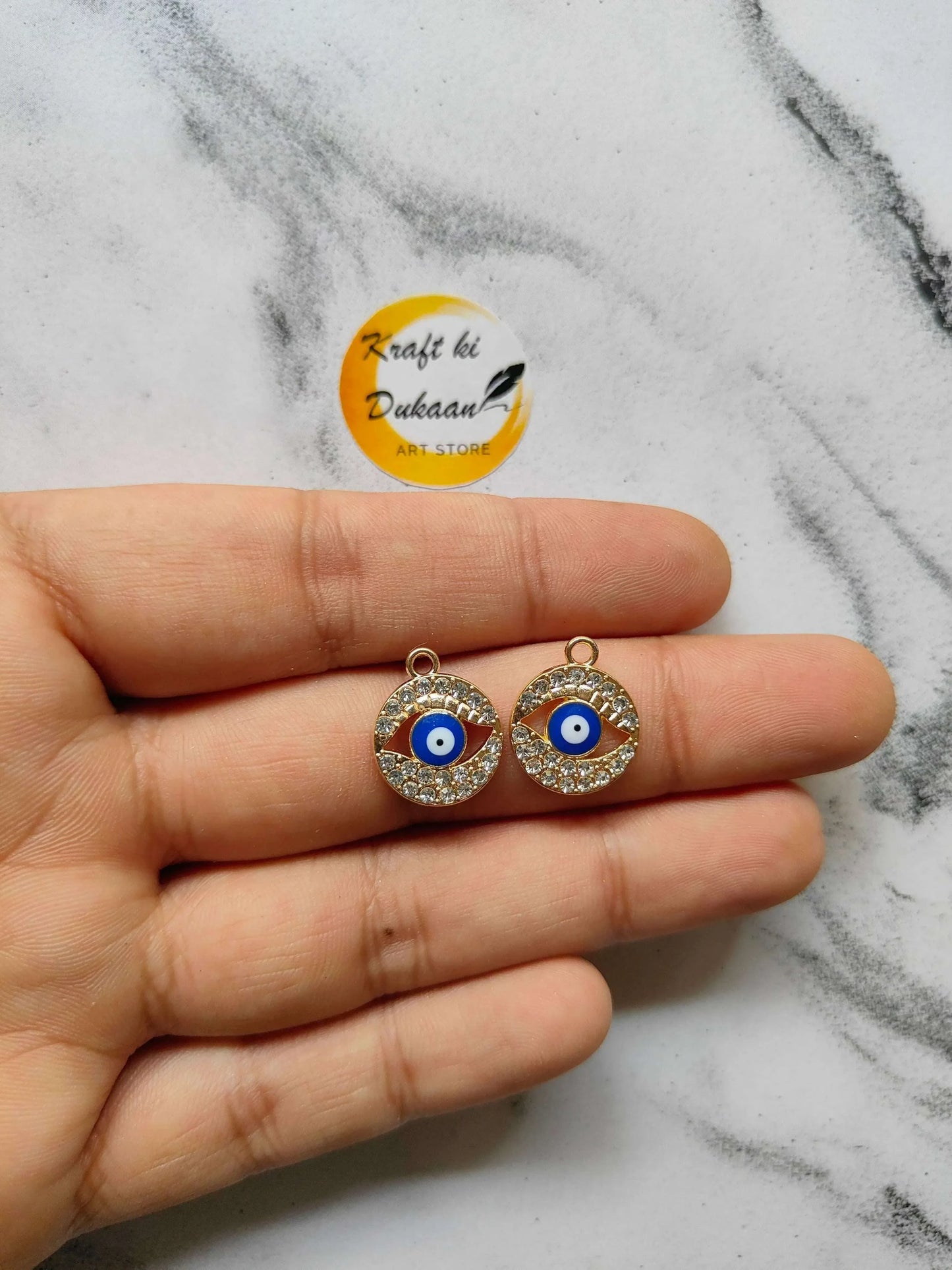 Gold-tone metal evil eye pendant pair, blue eye center with rhinestone border, small loop