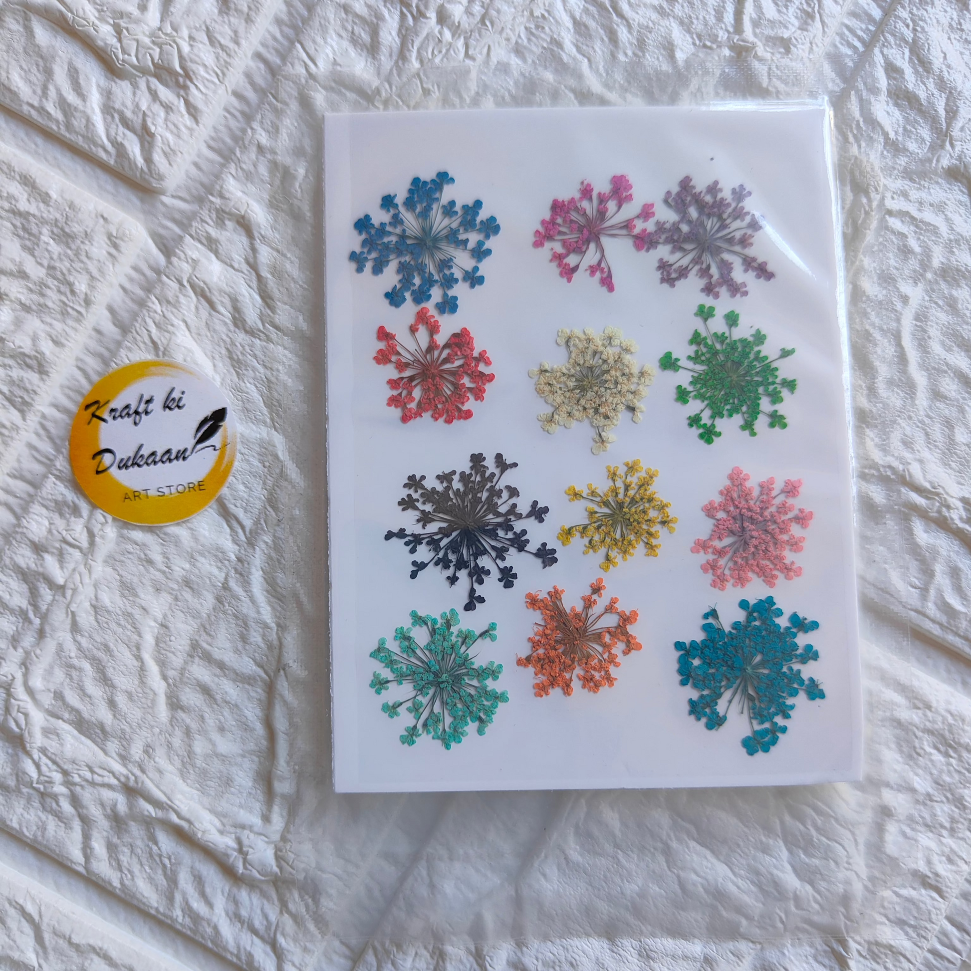 Assorted multi-colored pressed flowers arranged on a sheet for craft projects from Kraft ki Dukaan