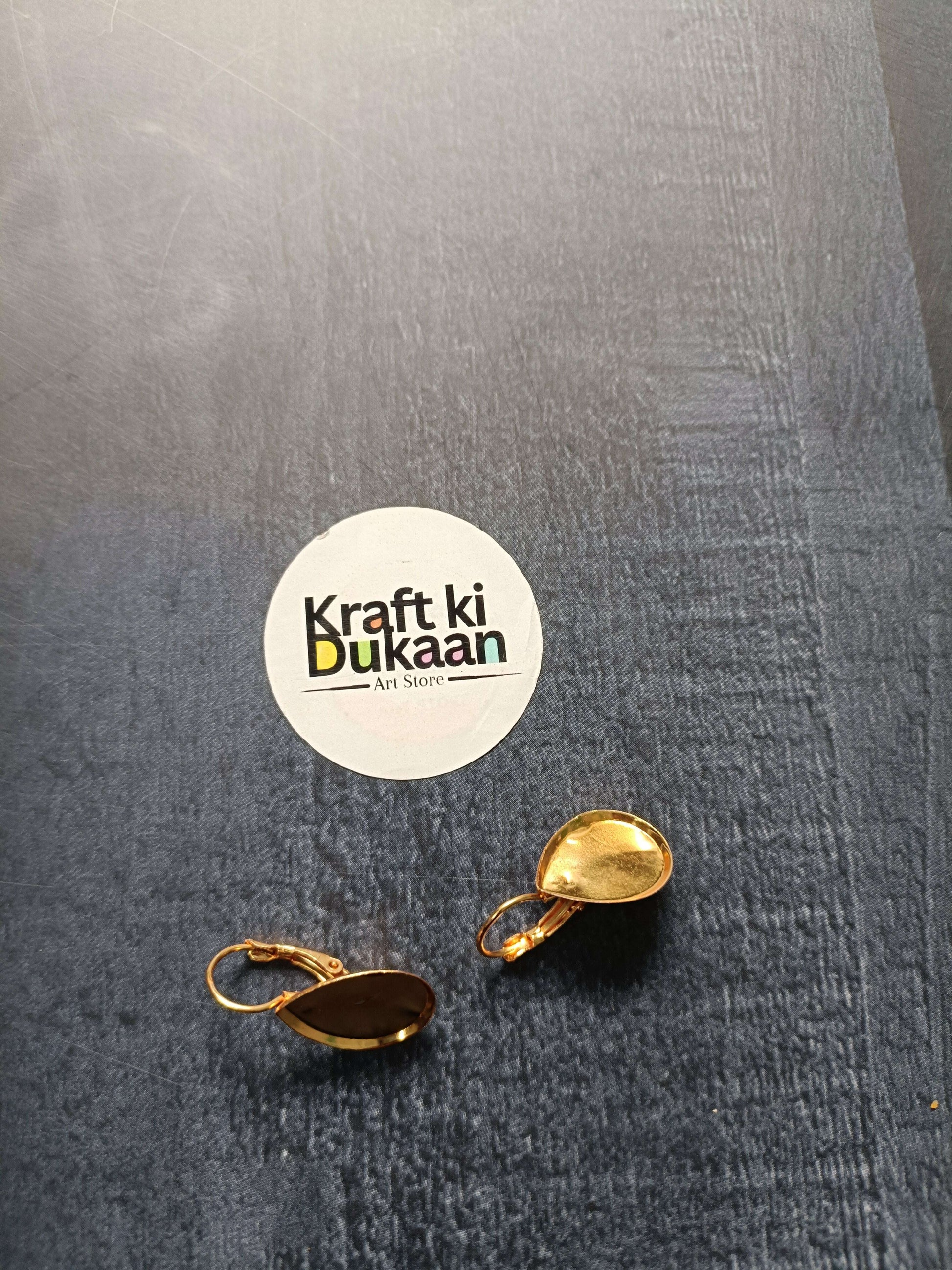 Gold-tone drop earring bases with oval settings: one dark brown, one golden yellow