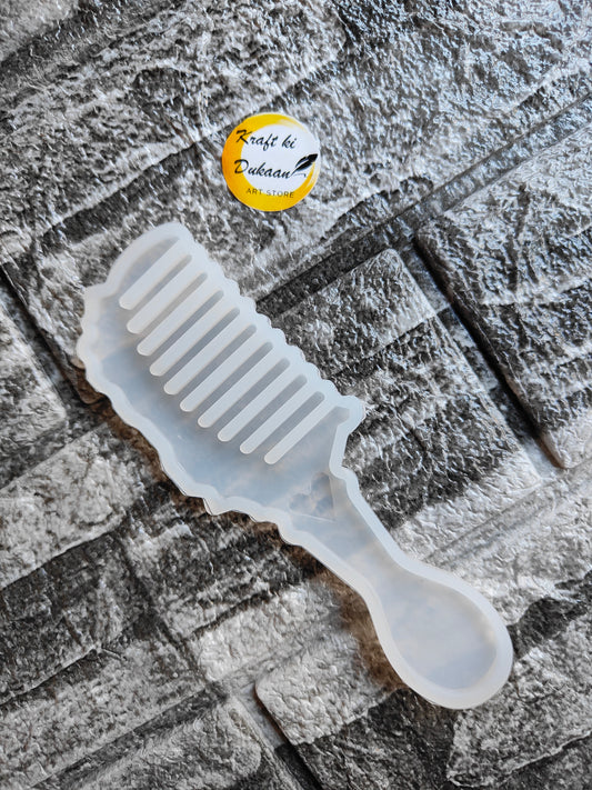 Clear silicone resin comb mold shaped like a handle comb on gray textured stone background