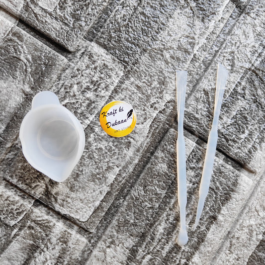 Kraft ki Dukaan resin mixing cup kit with silicone cup and two clear mixing sticks on textured surface