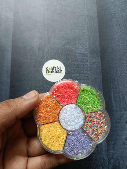 Round glitter box in hand, red, green, orange, yellow and purple glitter in 8 sections
