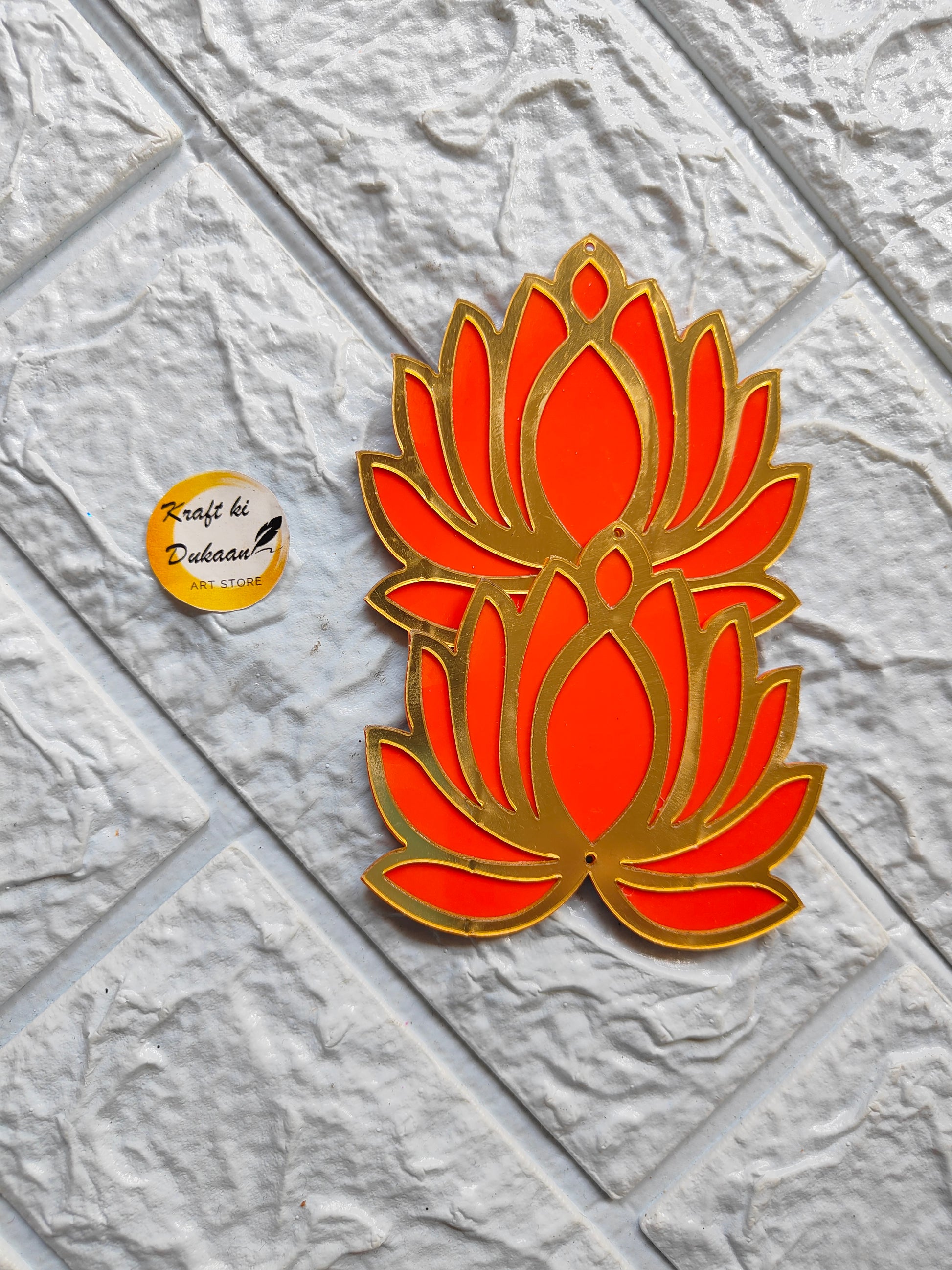 Acrylic lotus cutout with vibrant orange and gold design on textured white surface by Kraft ki Dukaan