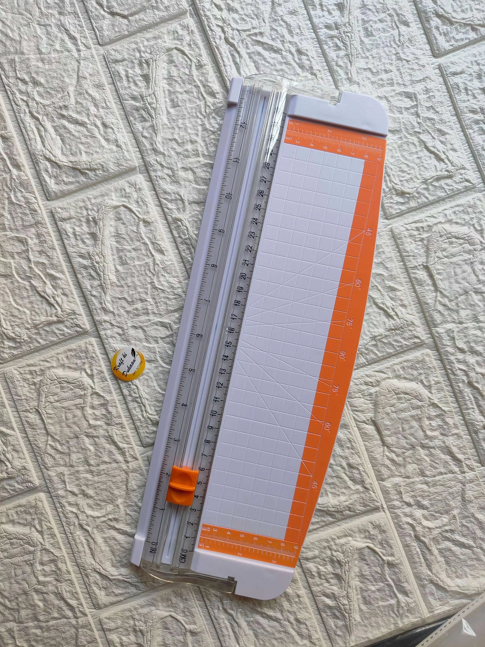 Paper trimmer with white cutting board, orange guide, and measurement ruler in frame