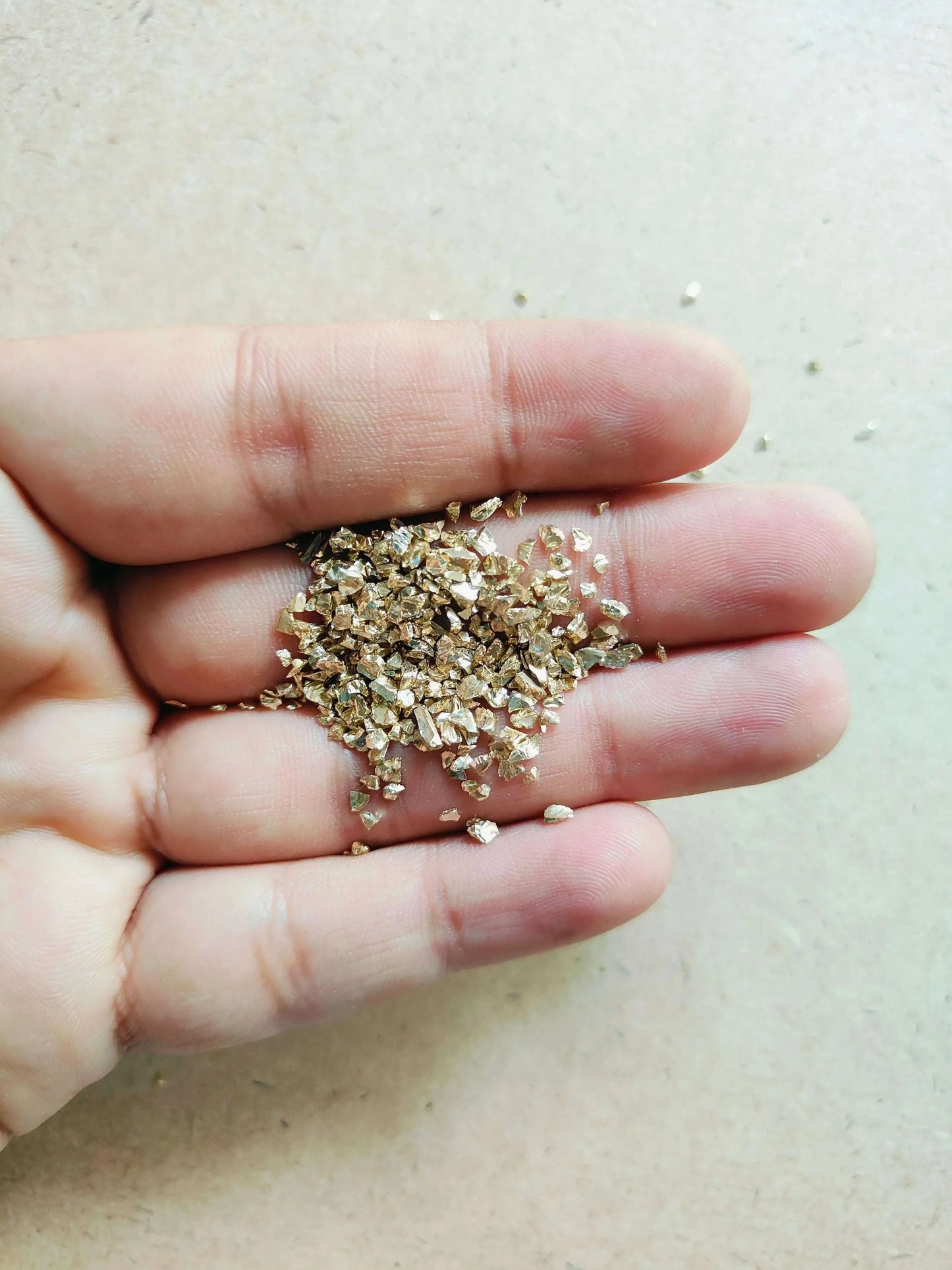 Close-up of light gold granules for resin art held in a hand, perfect for crafting projects