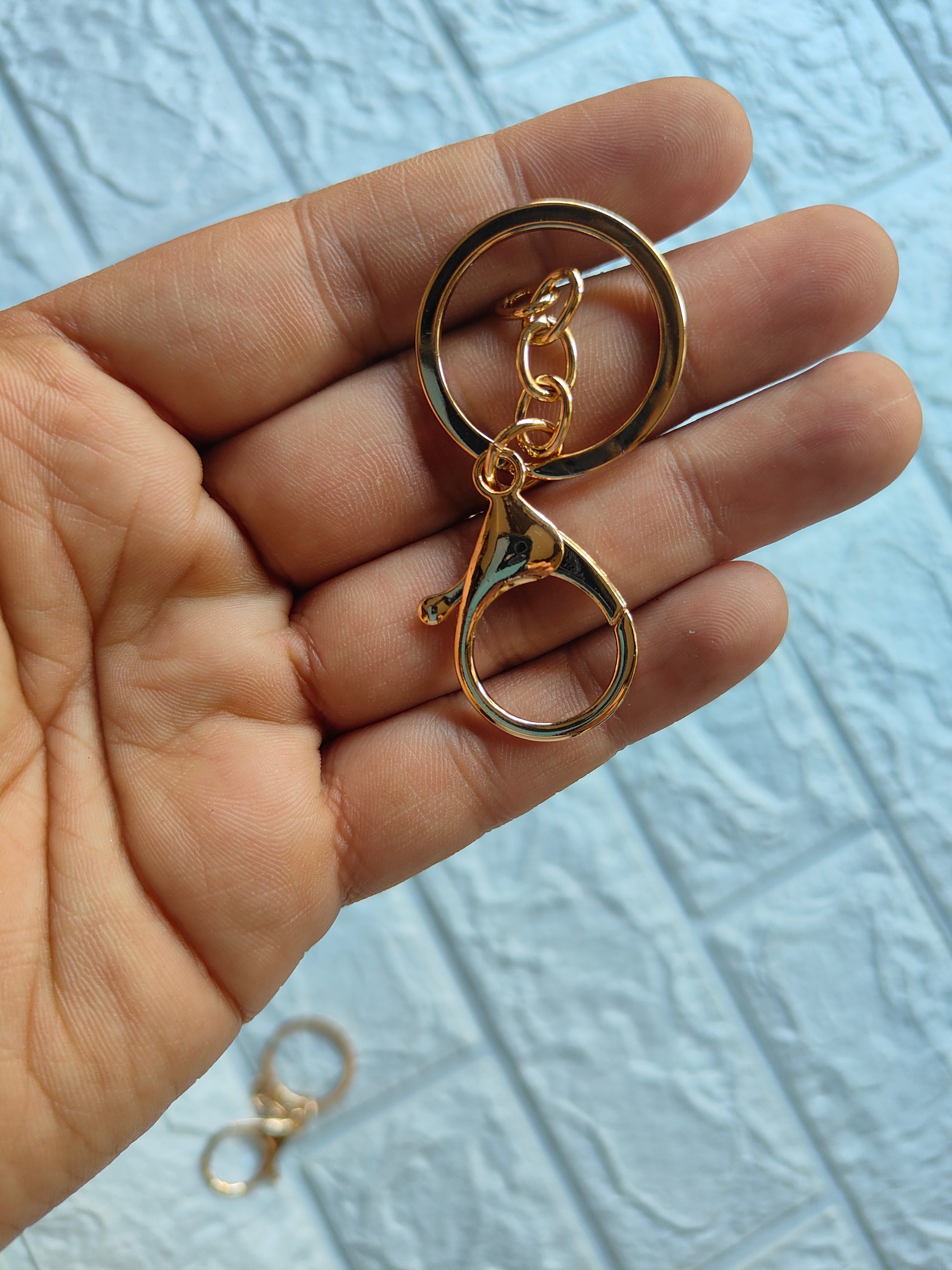 Elegant lobster clasp keychain in gold held in a hand with a smooth finish