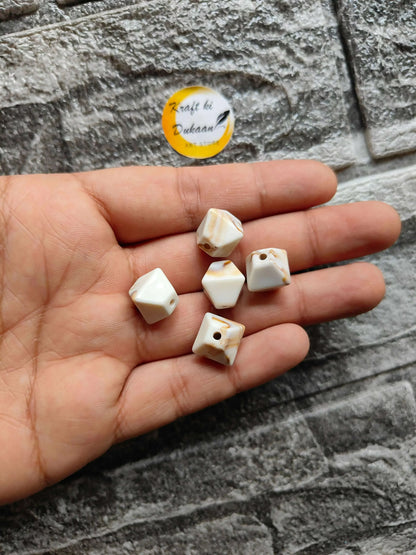 Marble hexagon beads pack: cream with brown veining, drilled holes, held in hand