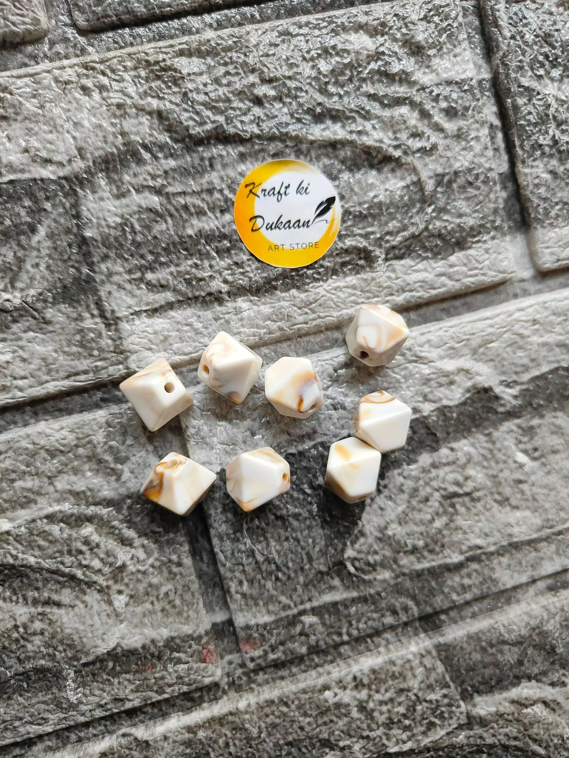 Scattered marble hexagon beads, cream with brown streaks, drilled holes visible