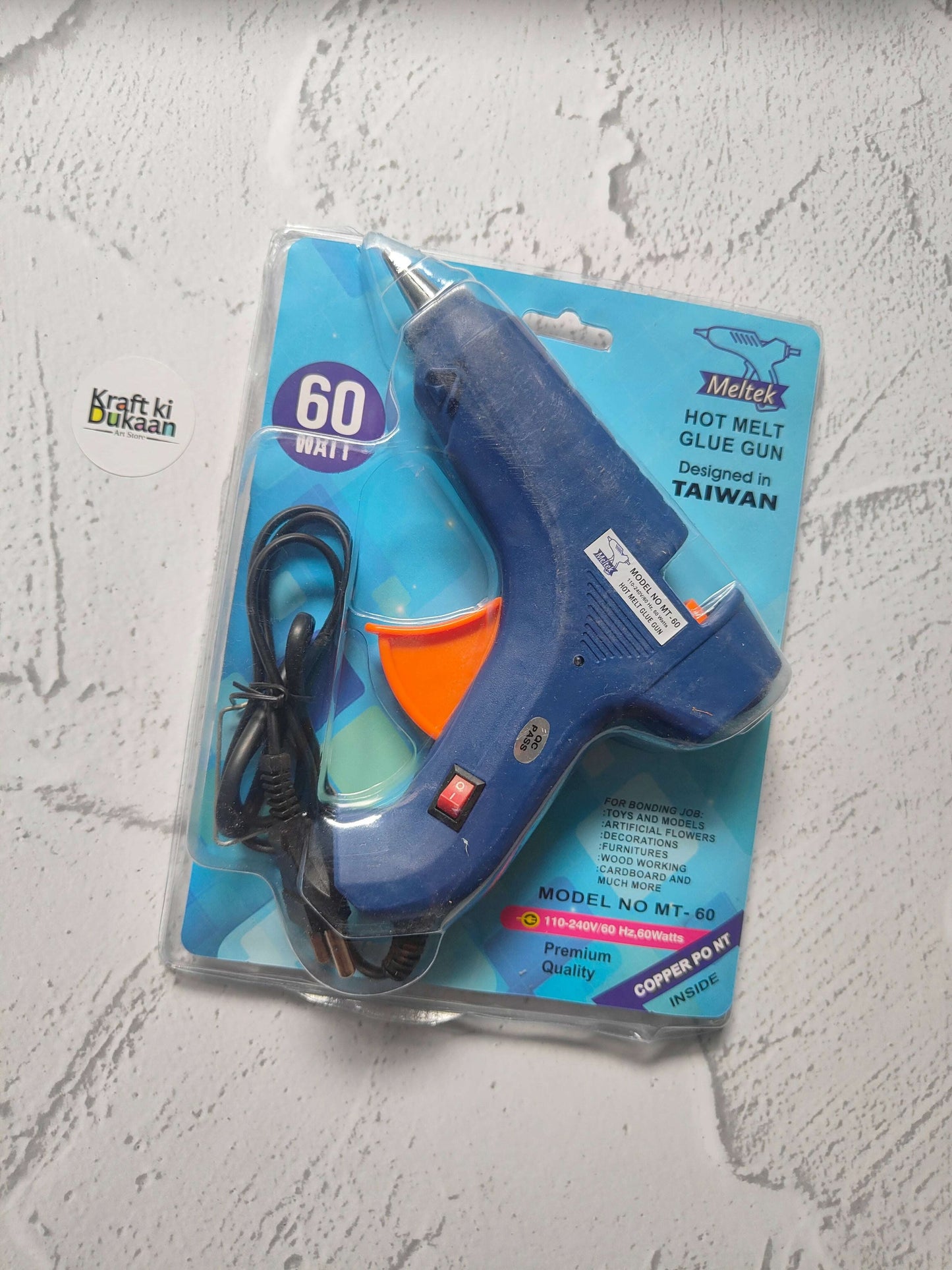 Hot melt glue gun blister pack, dark blue body with orange front and black power cord.