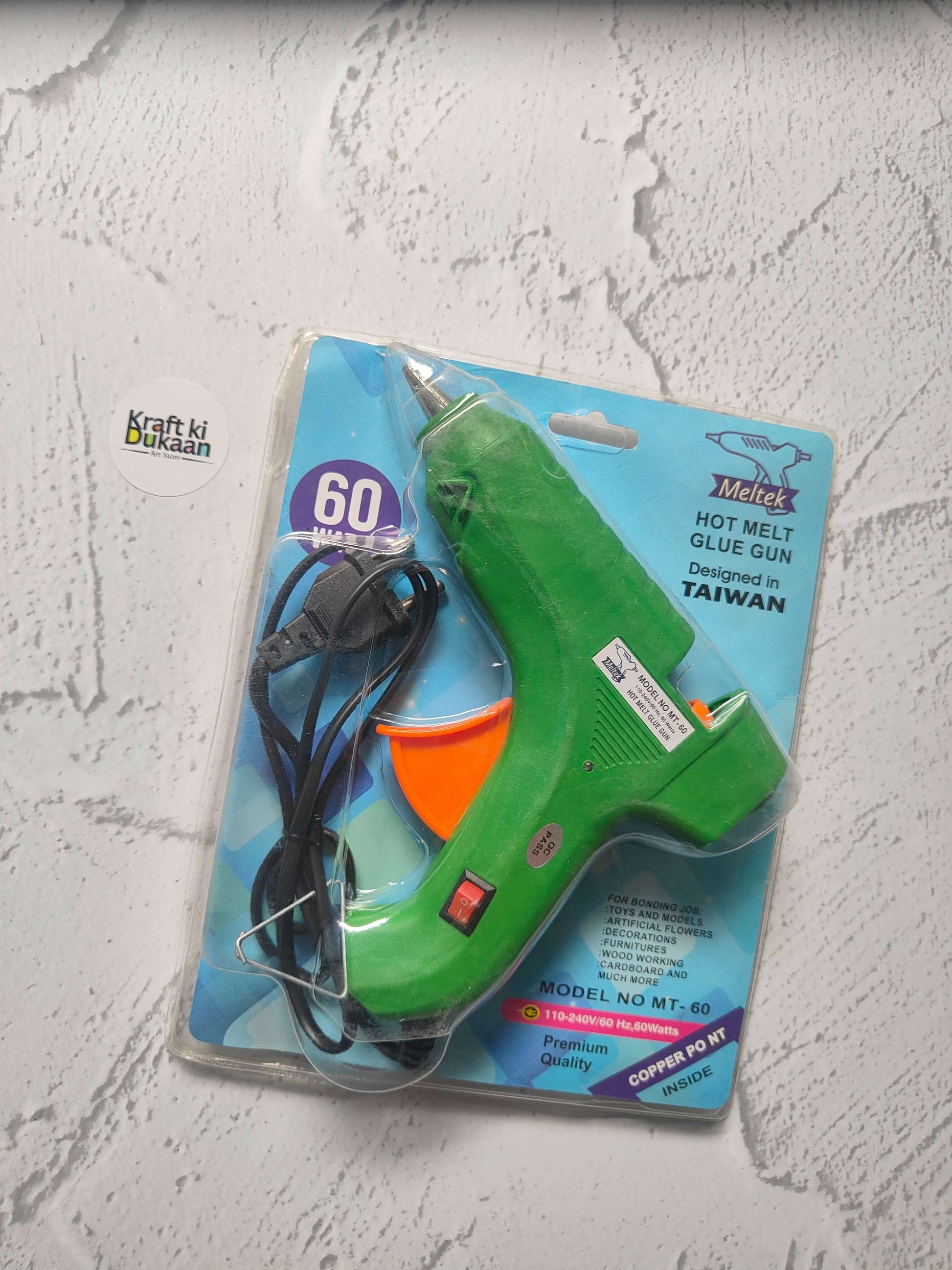 Hot melt glue gun blister pack, green body with orange front and black power cord.