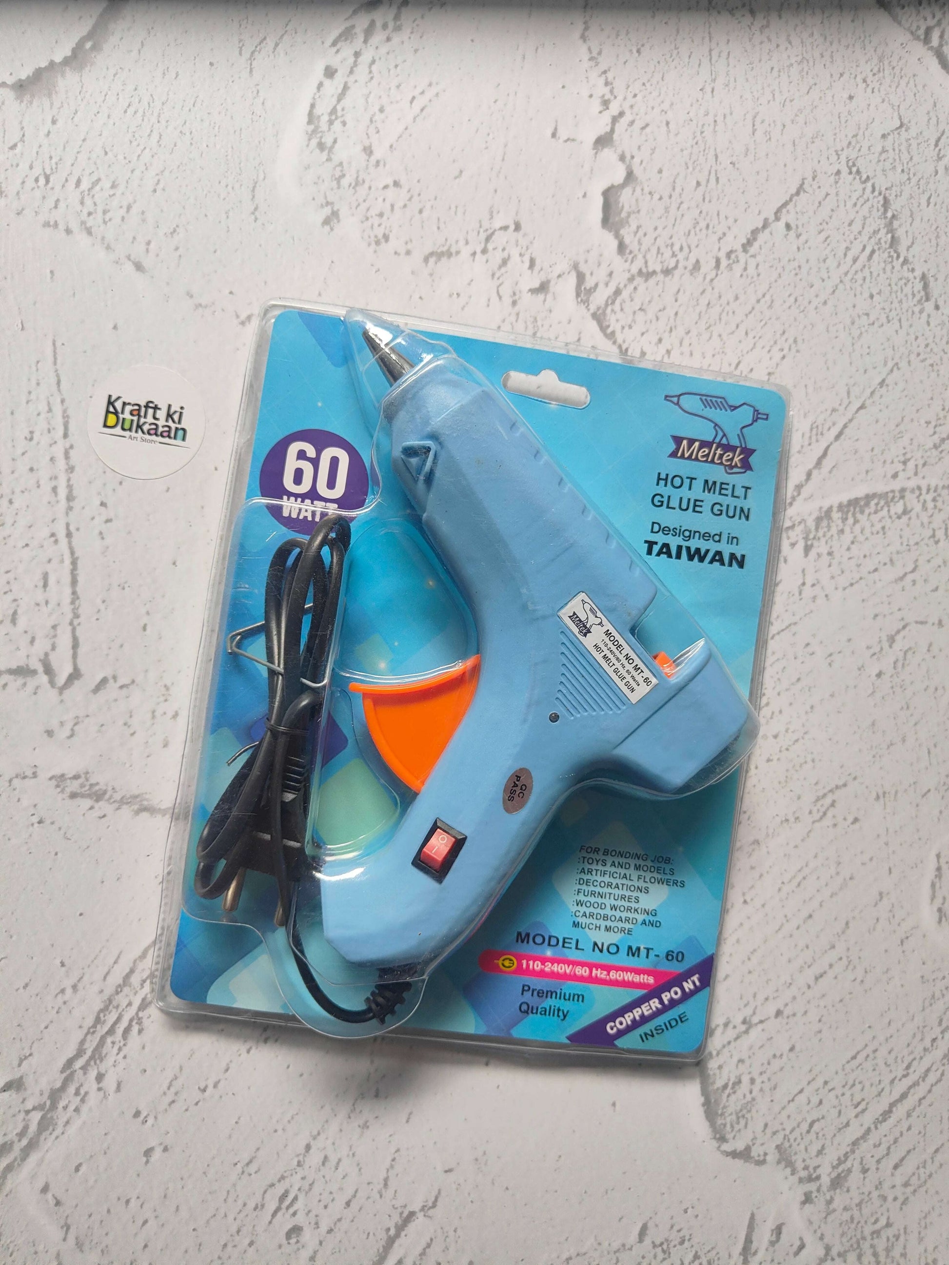 Hot melt glue gun blister pack, blue body with orange front and black power cord.