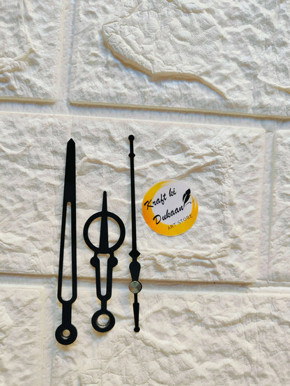 Metal clock hands set in black, with circular and pointed tips, displayed flat.
