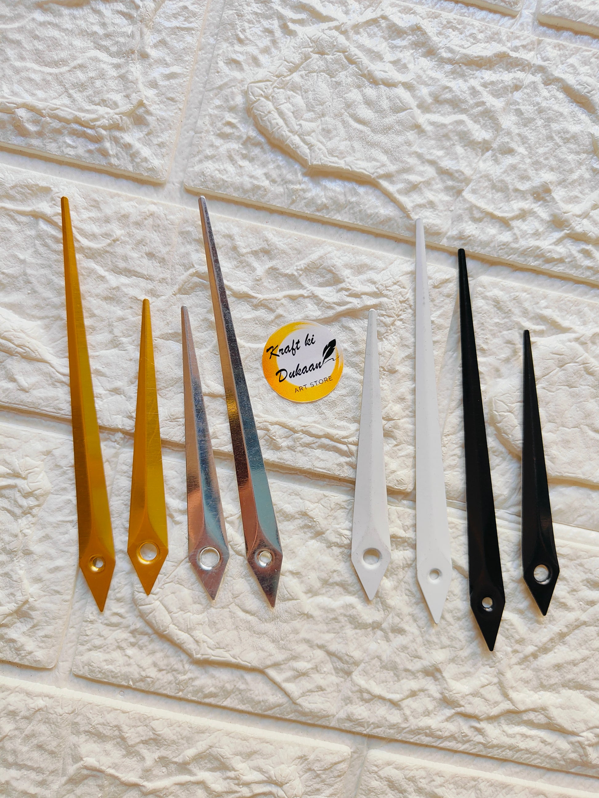 Variety of metal clock hands for crafts in different colors including gold, silver, white, and black
