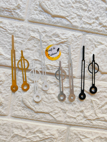 Collection of metal clock hands for crafts in gold, silver, and black colors on a textured background