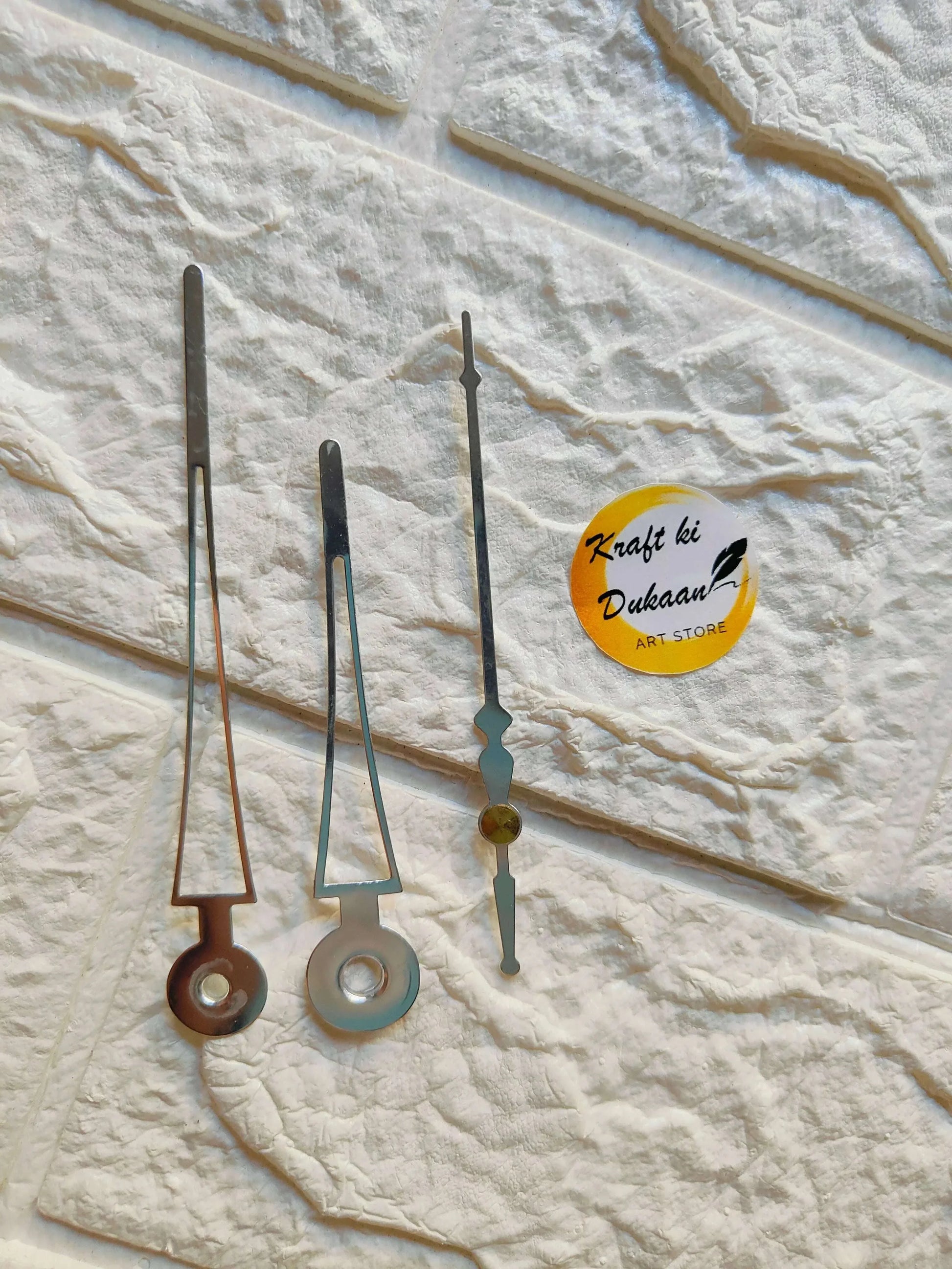 Metal clock hands set with silver, black, and teal/blue accents