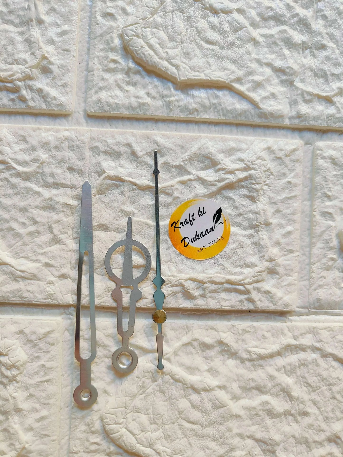 Metal clock hands set: silver-gray and black with an accent gold hand, flat view.