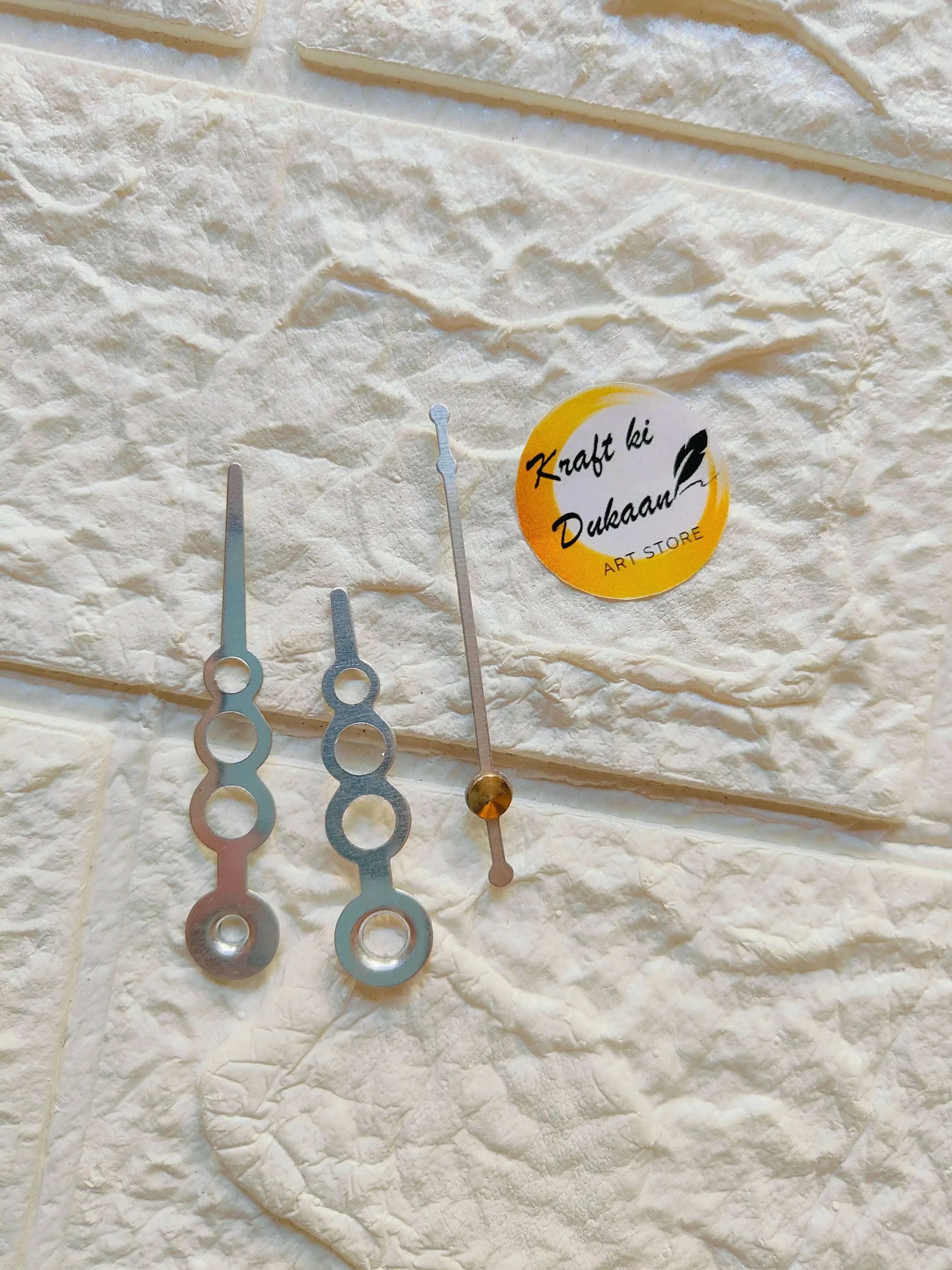 Metal clock hands set with ornate circular tips, blue and gold