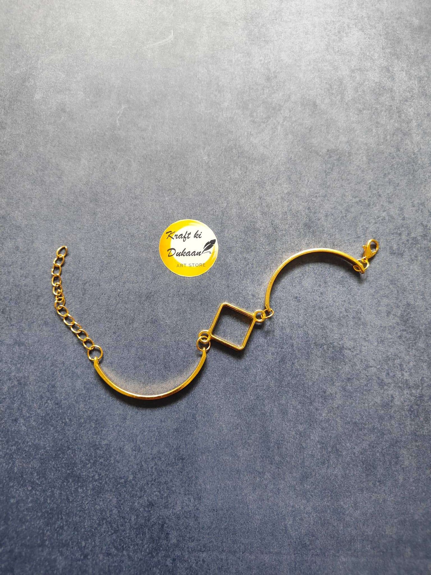 Gold metal bracelet with curved bar, square link charm, fine chain and lobster clasp