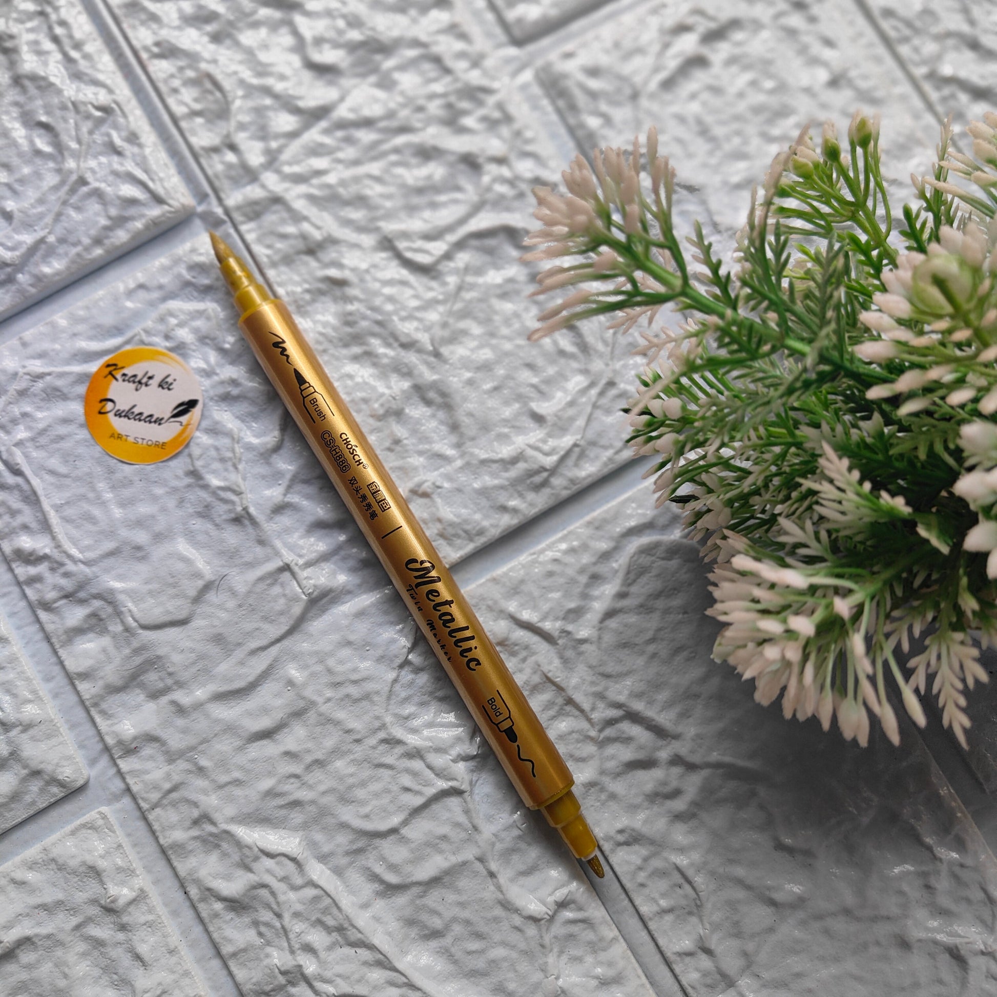 Kraft ki Dukaan metallic markers for crafts in gold color next to a green plant