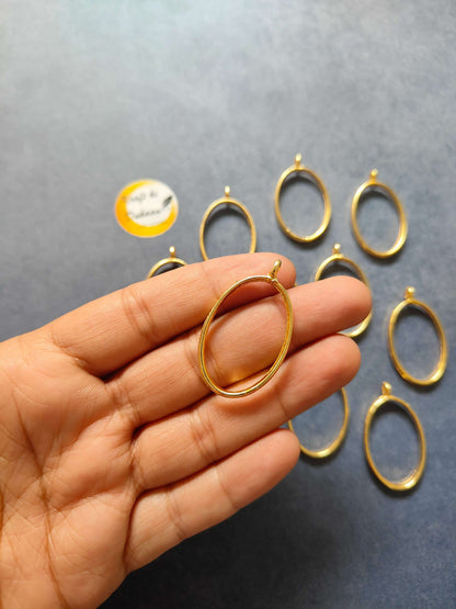 Gold oval pendant bezel held on fingertip, small top loop; 10pc set