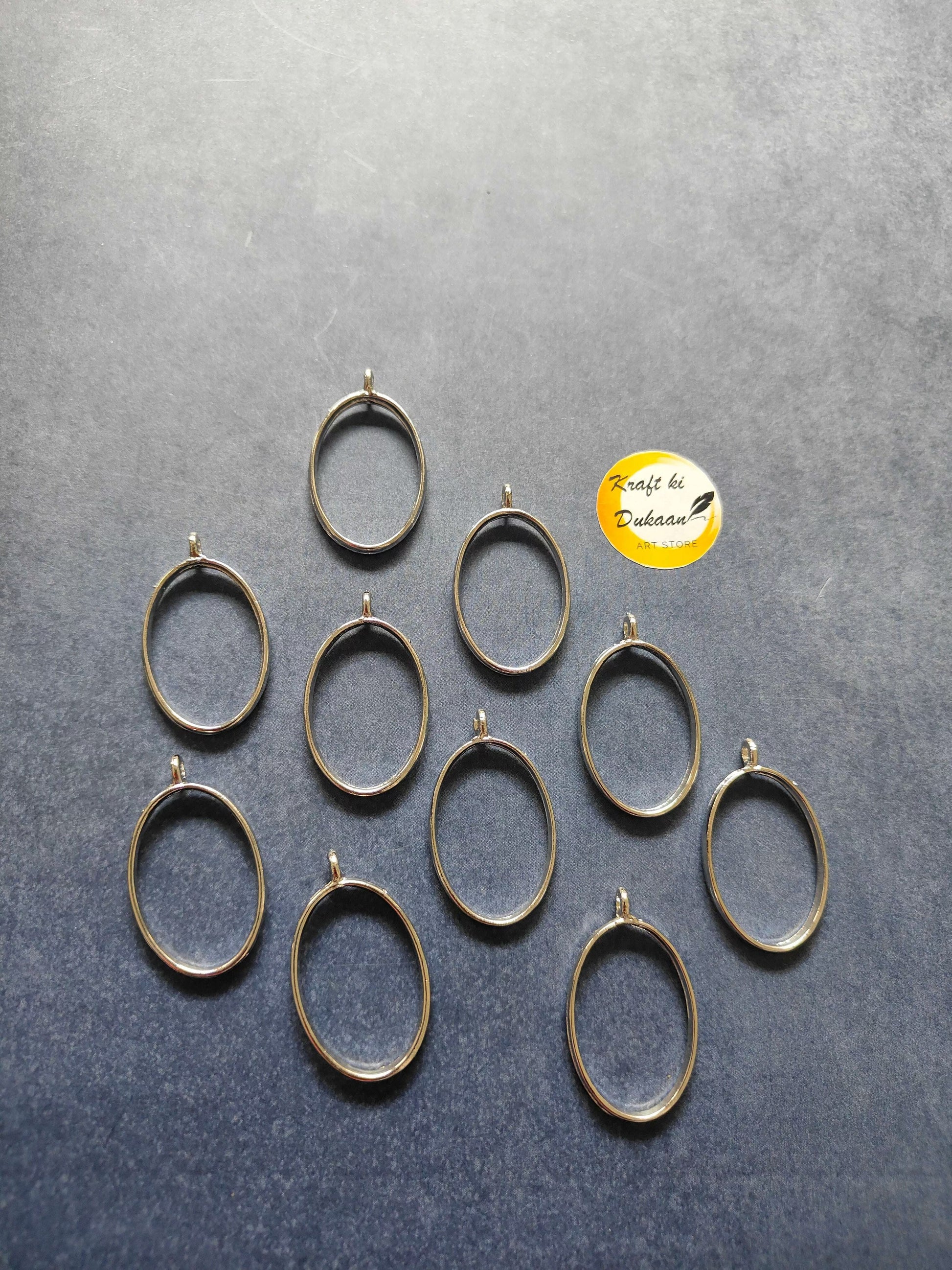 Gold-tone oval bezel pendant frames, 10-piece set laid out with top loops