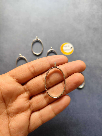 Silver oval bezel pendant held on fingertip, small top loop; 10pc set