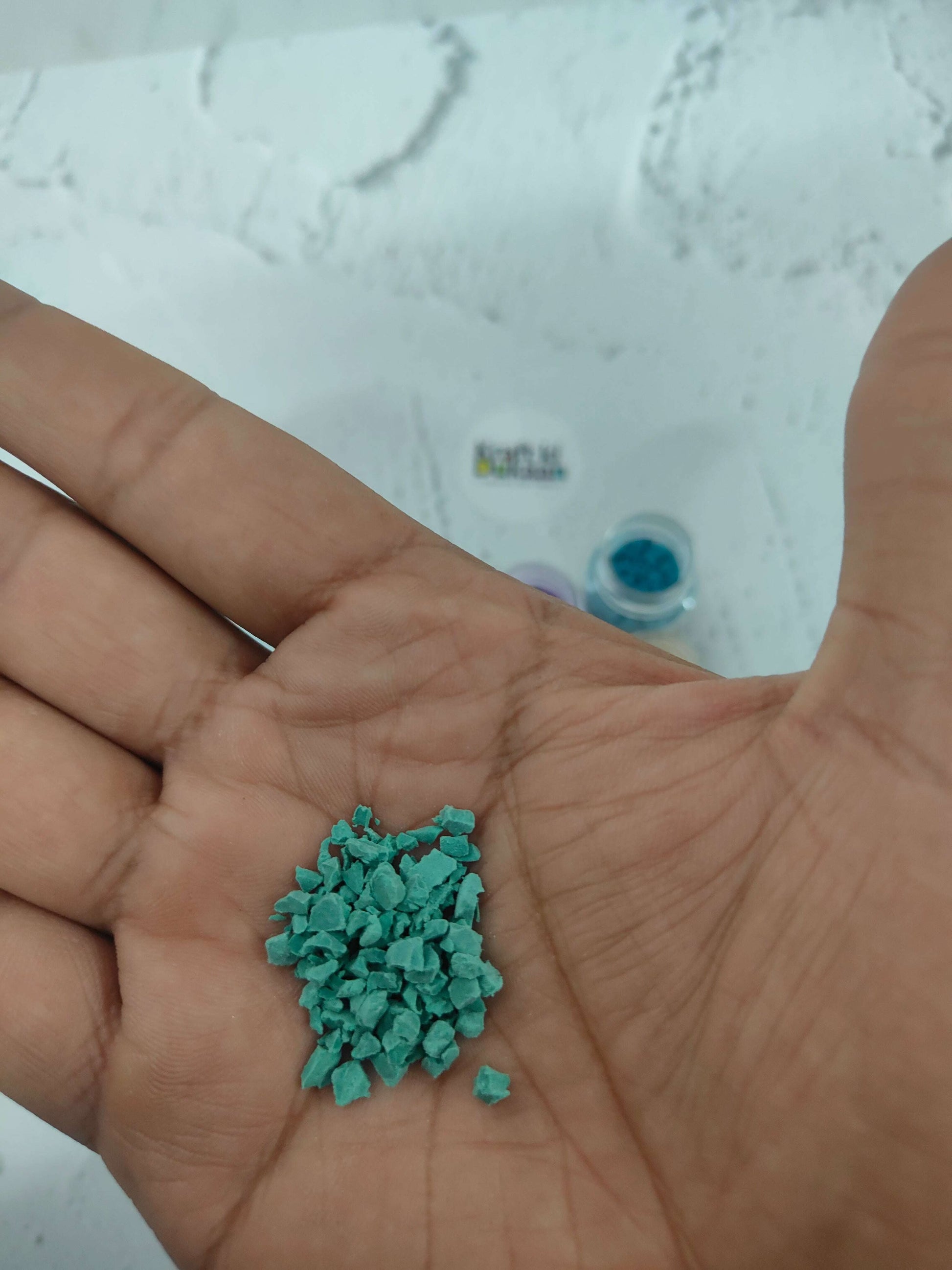Handful of teal rubber particles held in an open palm