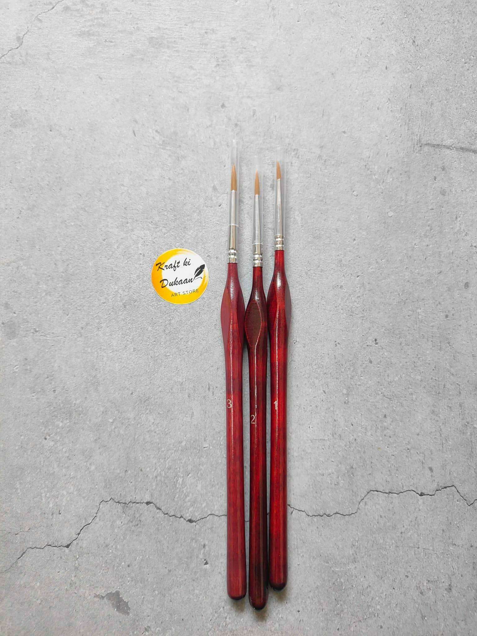 Three round paint brushes with reddish brown handles