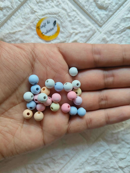 Pastel pearl beads in hand: small round beads in blue, pink, cream, and yellow