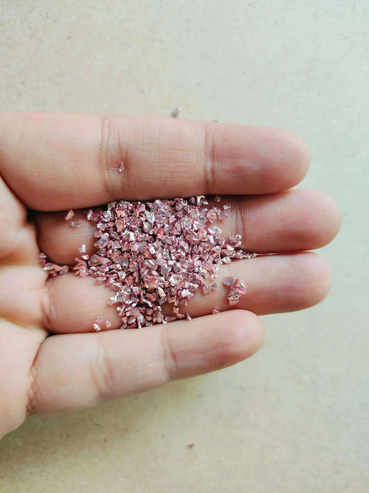 Hand holding pink stone granules for resin art, showcasing texture and color for creative projects