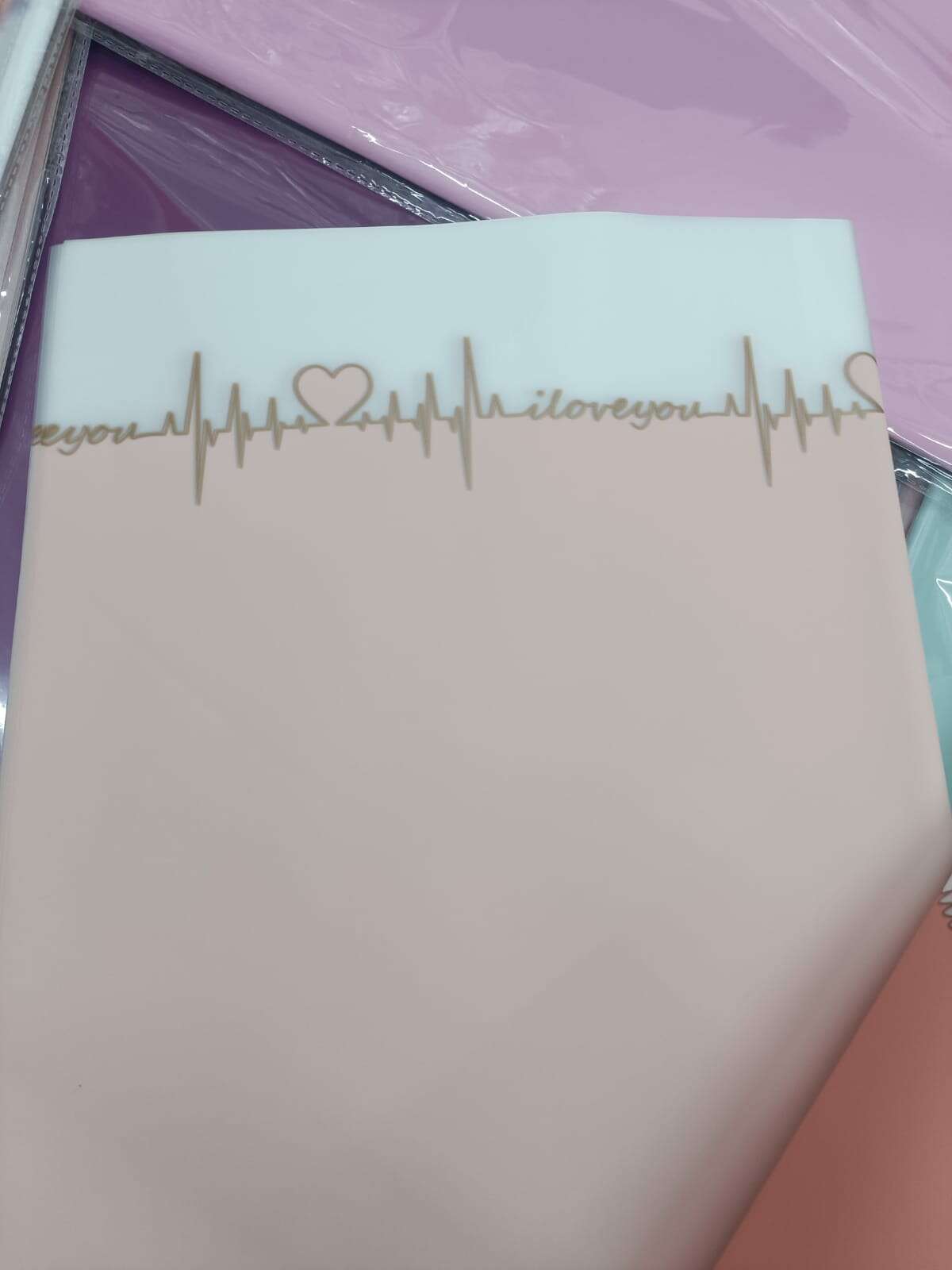 Pastel blue wrapping paper sheet with gold ECG line and heart, design across top