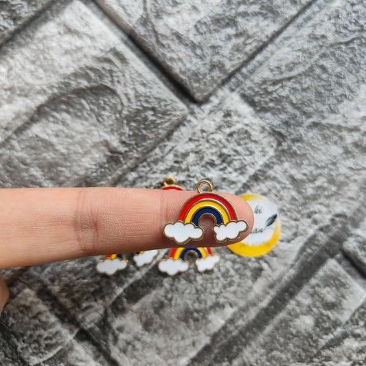 Rainbow metal charm with red-yellow-blue arc and white cloud detail, held in hand